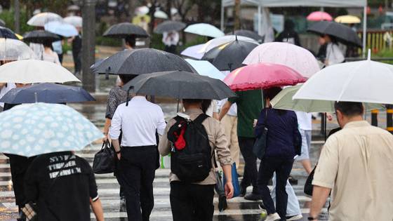 서울 종로구 광화문 네거리에서 우산을 쓴 시민들이 길을 건너고 있다. 연합뉴스