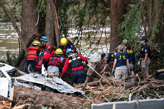 미 텍사스주 홍수 피해 지역에서 7일(현지시간) 미 연방수사국(FBI) 요원들이 지켜보는 가운데 멕시코 구조대원들이 수색 작업을 하고 있다. [AP]