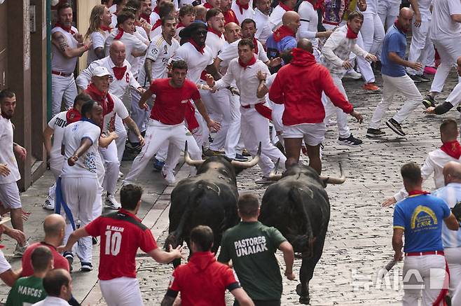 [팜플로나=AP/뉴시스] 7일(현지 시간) 스페인 팜플로나에서 열린 연례 산 페르민 축제 중 황소와 달리기(엔시에로) 참가자들이 골목길을 달리고 있다. 2025.07.07.