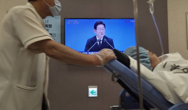 서울 한 대학병원에서 한 환자가 이재명 대통령의 첫 기자회견 방송이 나오는 가운데 침대에 실려 이동하고 있다. 연합뉴스