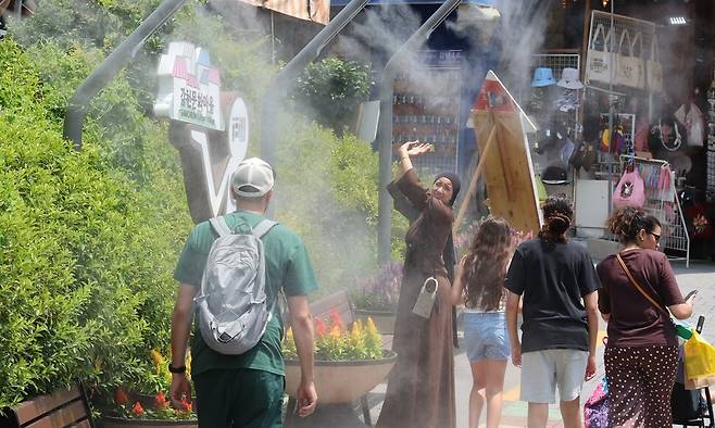 연일 열대야와 폭염이 이어지는 가운데 지난 8일 오후 부산 사하구 감천문화마을에서 외국인 관광객들이 쿨링 포그가 뿜어내는 물안개를 맞고 있다. 연합뉴스