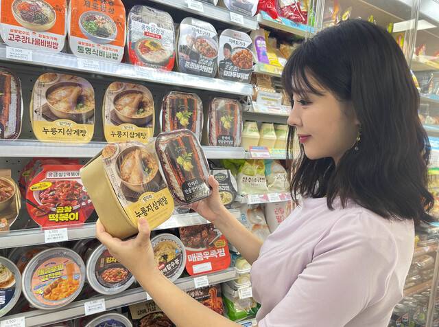 GS25에서 모델이 닭다리누룽지삼계탕과 한마리민물장어덮밥을 살펴보고 있다. GS리테일 제공.
