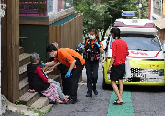 Emergency responders care for an older adult who collapsed near Seoul Station in Yongsan District, central Seoul, during the record-breaking heatwave on July 9. [YONHAP]