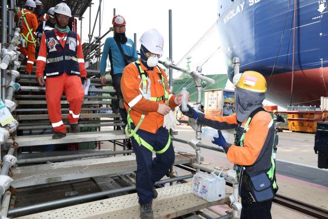 한화오션 안전관리자가 '찾아가는 얼음생수' 활동으로 오후 쉬는 시간 휴식을 위해 하선하는 작업자들에게 얼음 생수를 전달하고 있다. 한화오션 제공