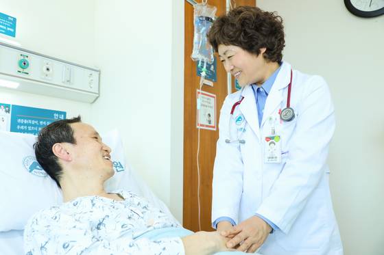 이영이 강릉아산병원 입원전담전문의가 이달 3일 63병동에 입원 중인 위암 환자의 손을 잡고 질병 상태를 설명하고 있다. 이 교수는 일본과 한국 의사 면허를 가진 보기 드문 의사이다. [사진 강릉아산병원]