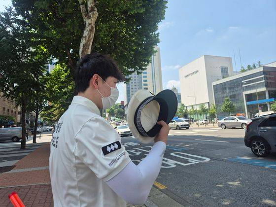 9일 오전 10시30분쯤 서울 강남구 청담동 경기고 사거리 동호대교 방면 도로에서 교통 단속을 하던 서울 강남경찰서 윤덕기 경장(34)이 그늘에서 숨을 돌리며 모자로 부채질을 하고 있다. 오소영 기자