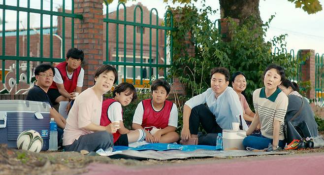 <여름이 지나가면> 속 마을 사람들이 각자의 아이들과 함께 모여 있다. 이들의 시선 끝엔, 영문과 영준 형제가 있다. 엣나인필름 제공