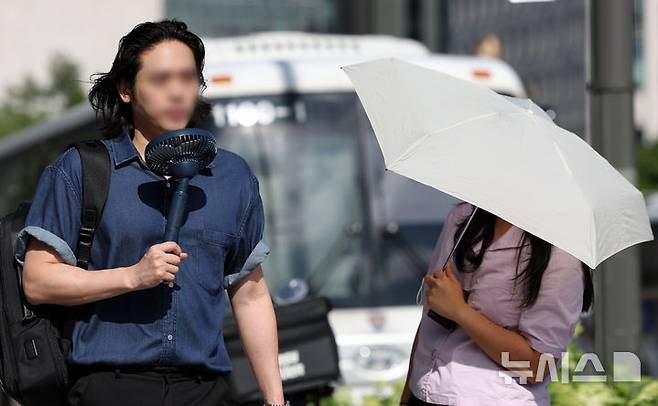 [서울=뉴시스] 조성우 기자 = 폭염이 계속되는 10일 서울 종로구 거리에서 한 시민이 선풍기로 더위를 식히며 이동하고 있다. 2025.07.10. xconfind@newsis.com