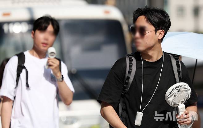 [서울=뉴시스] 조성우 기자 = 폭염이 계속되는 10일 서울 종로구 거리에서 한 시민이 선풍기로 더위를 식히며 이동하고 있다. 2025.07.10. xconfind@newsis.com