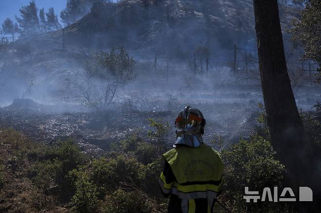[마르세유=AP/뉴시스] 8일(현지 시간) 프랑스 남부 마르세유 인근에서 한 소방관이 산불 진화 작업을 벌이고 있다. 산불이 확산하면서 마르세유 공항과 철도 운행이 중단됐으며 프랑스 기상청은 인근 지역에 적색경보를 발령했다. 2025.07.09.