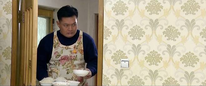 북한 드라마 '백학벌의 새봄' 중 한 장면 (서울=연합뉴스) 북한 드라마 '백학벌의 새봄' 속 남성이 꽃무늬 앞치마를 입고 아내와 딸에게 밥을 차려주고 있다. 2025.7.10 [조선중앙TV 캡처]