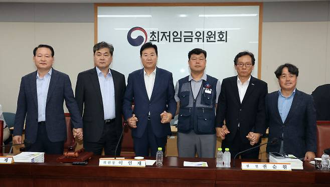 이인재 최저임금위원장(왼쪽 두 번째)이 10일 정부세종청사에서 열린 제12차 전원회의에서 내년 최저임금을 시간당 1만320원으로 17년 만에 합의 결정한 뒤 공익위원-사용자위원-근로자위원과 손을 잡고 있다. (사진=연합뉴스)