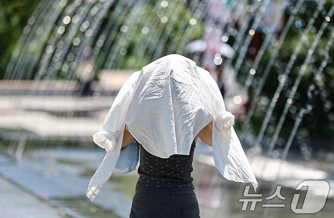 폭염이 이어진 전날 서울 종로구 광화문광장에서 한 시민이 옷으로 얼굴을 가린채 이동하고 있다. 2025.7.10/뉴스1 ⓒ News1 김도우 기자