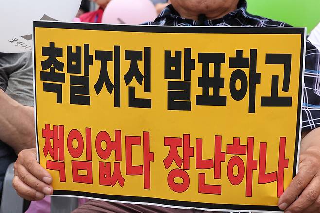 경북 포항 지진 정신적 손해배상 소송의 항소심 패소 판결과 관련해 ‘포항지진 범시민대책본부’가 지난달 13일 포항 육거리 인근 중앙상가에서 개최한 시민궐기대회에서 시민들이 항의 손팻말을 들고 있다. 연합뉴스