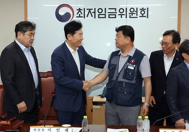 최저임금위원회 사용자위원 운영위원인 류기정 한국경영자총협회 전무(왼쪽)와 근로자위원 운영위원인 류기섭 한국노총 사무총장이 10일 정부세종청사에서 열린 제12차 전원회의에서 내년 최저임금을 시간당 1만320원으로 17년 만에 합의로 결정한 뒤 악수하고 있다. 왼쪽은 이인재 위원장, 오른쪽은 이명로 중소기업중앙회 인력정책본부장 [연합]