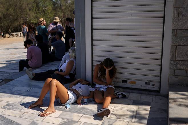 그리스 아테네의 낮 기온이 40도를 넘을 것으로 예상된 지난 9일(현지시간) 아크로폴리스 유적지 티켓 창구 앞에서 관광객들이 그늘을 찾아 쉬고 있다. [로이터]