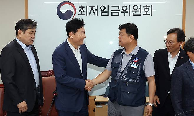 최저임금위원회 사용자위원 운영위원인 류기정 한국경영자총협회 전무(왼쪽)와 근로자위원 운영위원인 류기섭 한국노총 사무총장이 10일 정부세종청사에서 열린 제12차 전원회의에서 내년 최저임금을 시간당 1만320원으로 17년 만에 합의로 결정한 뒤 악수하고 있다. 왼쪽은 이인재 위원장, 오른쪽은 이명로 중소기업중앙회 인력정책본부장. 연합뉴스