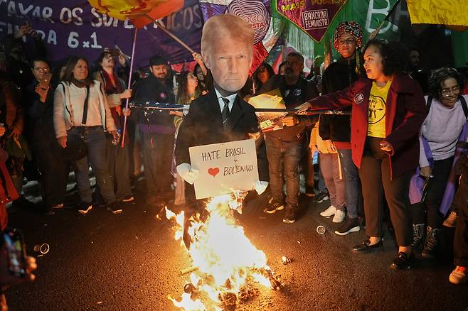 루이스 이나시우 룰라 다 시우바 브라질 대통령의 지지자들이 지난 10일(현지시각) 상파울루에서 시위를 벌이면서 50% 관세 부과를 발표한 도널드 트럼프 미국 대통령 인형을 불태우고 있다. /AP·연합뉴스