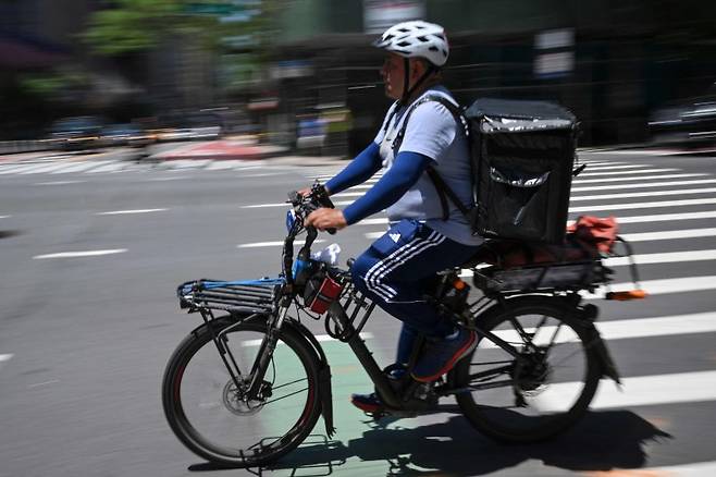 지난달 24일(현지시간) 미국 뉴욕 맨해튼에서 음식 배달업 종사자가 도심을 질주하고 있다.AFP연합뉴스