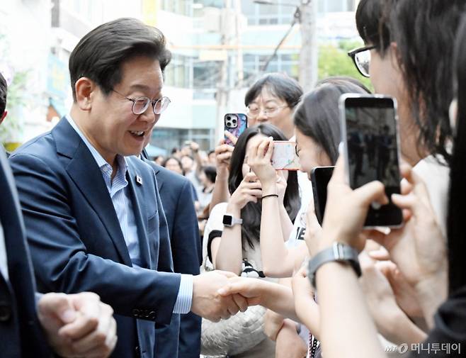 [서울=뉴시스] 최동준 기자 = 이재명 대통령이 11일 외식 행사를 위해 서울 종로구 한 식당으로 걸어서 이동하던 중 시민들과 인사하고 있다.  이 대통령은 SNS에 식사 계획을 알리며 "이처럼 어려운 시기에 21일부터 시행되는 민생회복 소비쿠폰 정책이 내수 진작과 지역 경제 활성화에 활력을 불어넣길 기대한다"고 밝혔다. (대통령실통신사진기자단) 2025.07.11. photocdj@newsis.com /사진=최동준