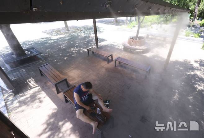 [서울=뉴시스] 김근수 기자 = 연일 폭염이 계속되는 가운데 11일 서울 영등포구 여의도 공원에서 한 시민이 쿨링포그를 아래서 더위를 피하고 있다. 2025.07.11. ks@newsis.com