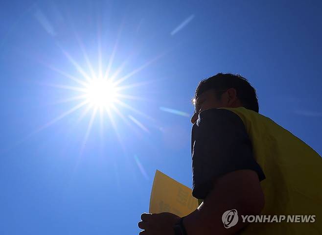 11일 서울 종로구 정부서울청사 앞에서 정부 규제개혁위원회(규개위)의 폭염 규칙 통과 촉구 기자회견을 하는 민주노총 조합원 위로 뙤약볕이 내리쬐고 있다. [연합뉴스 자료사진]