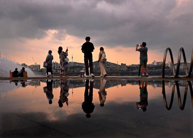 불볕더위와 폭우가 번갈아 왔던 8일 반포 한강공원에 비바람이 물러가자, 먹구름 사이로 붉은 노을이 번지며 사람들이 다시 모여들기 시작했다.
