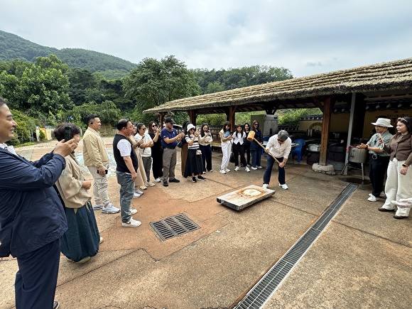 14일 마비정벽화마을을 찾은 태국여행업협회 관계자가 전통 떡메치기를 체험 중이다 [사진=달성군]