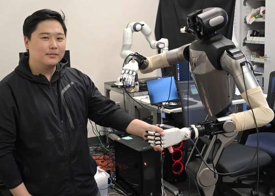 연구실에서 휴머노이드(인간형 로봇)와 악수하는 김지웅 스탠퍼드대 박사후 연구원. 존스홉킨스대에서 연구하던 시절 AI 로봇으로 담낭 수술을 하는데 성공했다. '로봇판 GPT'를 만드는 게 목표다. 사진 본인제공