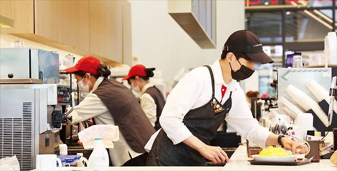 < “바쁘다 바빠” > 2026년 최저임금이 올해보다 290원 오른 1만320원으로 결정돼 최저임금의 80%로 책정되는 실업급여 하한액이 10년 만에 상한액(하루 6만6000원)을 추월했다. 13일 서울 시내 한 카페에서 종업원이 음식을 만들고 있다.   연합뉴스