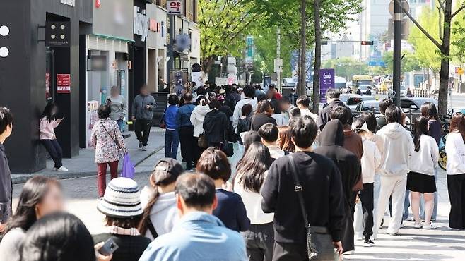 SK텔레콤 해킹 사태로 고객 이탈이 가속화되면서, 고객 유치를  위한 통신 3사 간의 과열 경쟁이 극심해지고 있다. SKT 대리점 앞에서 유심을 교체하려고 시민들이 줄을 서 기다리는 모습. [연합]