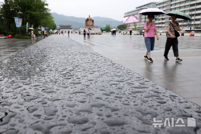[서울=뉴시스] 배훈식 기자 = 무더위를 식혀주는 비가 내린 13일 오후 서울 종로구 광화문광장에서 우산을 쓴 시민들이 발걸음을 옮기고 있다. 2025.07.13. dahora83@newsis.com