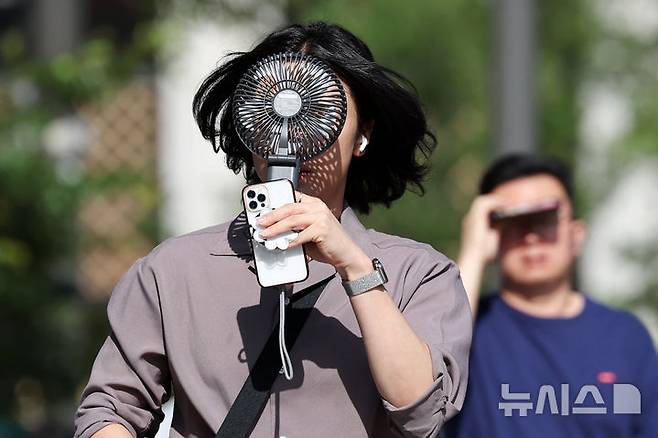 [서울=뉴시스] 조성우 기자 = 폭염이 계속되는 지난 10일 서울 종로구 거리에서 한 시민이 선풍기로 더위를 식히며 이동하고 있다. 2025.07.10. xconfind@newsis.com