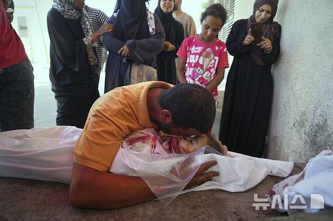 [가자지구=AP/뉴시스] 가자지구 데이르 알발라에 있는 '프로젝트 호프'가 운영하는 의료 클리닉 앞에서 영양 보충제를 기다리다 이스라엘의 공습으로 숨진 딸의 시신 앞에서 슬퍼하고 있다. 이번 공습으로 여성 두 명과 어린이 다섯 명을 포함해 총 10명이 숨졌다.