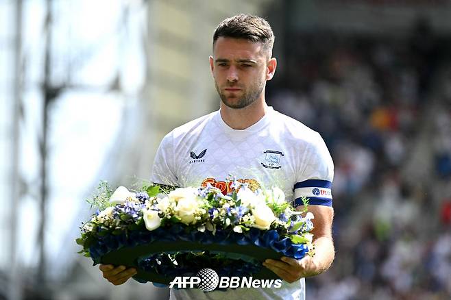 프레스턴 노스 엔드의 주장 벤 화이트먼이 13일(한국시간) 영국 랭커셔주 프레스턴의 딥데일에서 열린 리버풀과의 프리시즌을 앞두고 디오구 조타를 추모하는 근조화한을 들고 경기장에 입장하고 있다. /AFPBBNews=뉴스1