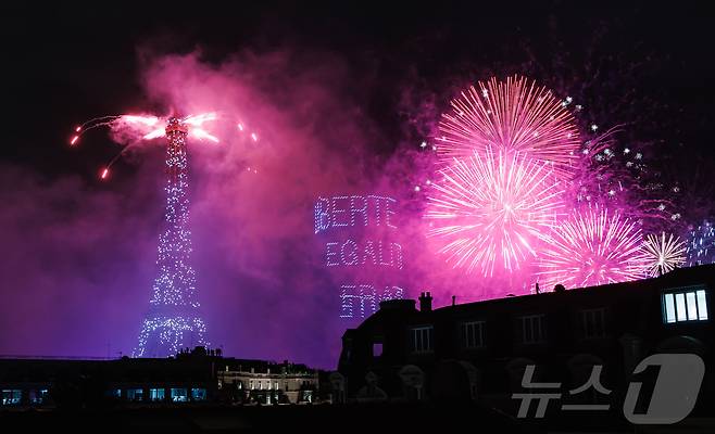 14일(현지시간) 프랑스 혁명 기념일(바스티유 데이)을 기념하기 위해 에펠탑에 펼쳐진 불꽃놀이 쇼에서 1천100대의 드론이 프랑스의 국가 모토인 ‘자유・평등・박애’(Liberté ・ Égalité ・ Fraternité)를 파리 상공에 새기며 불꽃과 함께 빛의 향연을 펼치고 있다. 2024.7.15/뉴스1 ⓒ News1 이준성 기자