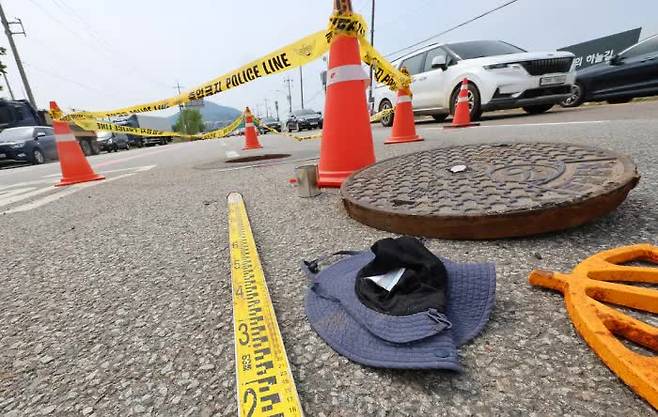 A hat and work tools lie next to a manhole in Byeongbang-dong, Gyeyang District, Incheon, where a 48-year-old man surnamed Lee was rescued in cardiac arrest and another man in his 50s went missing on July 6. Lee was declared brain-dead eight days later. / Yonhap