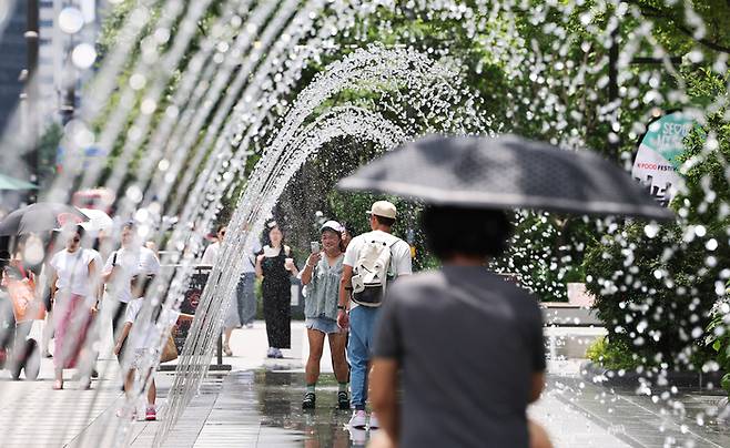고온다습한 찜통더위가 이어지는 가운데 서울 종로구 광화문 광장을 찾은 사람들이 바닥 분수에서 더위를 식히고 있다. [뉴스1]