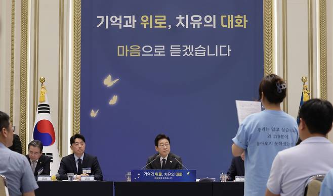 President Lee Jae Myung, center, listens to a statement by a representative of bereaved families of the Jeju Air crash of Dec. 29, 2024, at a meeting with some 200 family members and victims of major disasters at the Blue House in central Seoul on July 16. [JOINT PRESS CORPS]
