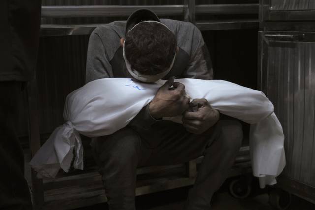 15일 가자지구 알 시파 병원에서 팔레스타인 시민 호셈 아잠이 이틀 전 이스라엘군의 공습으로 사망한 아들 아미르의 주검을 손에 끌어안은 채 울고 있다. AP 연합뉴스