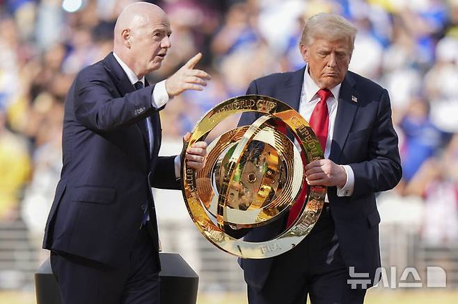 [이스트 러더퍼드=AP/뉴시스] 도널드 트럼프(오른쪽) 미국 대통령과 잔니 인판티노 국제축구연맹(FIFA) 회장이 13일(현지 시간) 뉴저지주 이스트 러더퍼드의 메트라이프 스타디움에서 열린 2025 FIFA 클럽 월드컵 첼시(잉글랜드)와 파리 생제르맹(PSG, 프랑스)의 결승전이 끝난 후 우승컵을 함께 들고 이동하고 있다. 첼시가 PSG를 3-0으로 완파하고 우승컵을 들어 올렸다. 2025.07.14.
