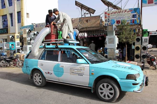 아프가니스탄 ‘47도 폭염’… 택시 지붕에 거대한 냉각기 - 아프가니스탄 칸다하르에서 14일(현지시간) 주민들이 택시 지붕에 설치된 ‘습식 공기 냉각 시스템’을 점검하고 있다. 이날 칸다하르 기온이 47도까지 치솟는 등 폭염이 이어지자 거대한 공기 냉각기를 차 지붕 위에 달아 열기를 식히는 장면이 많이 눈에 띄고 있다. 칸다하르 EPA 연합뉴스