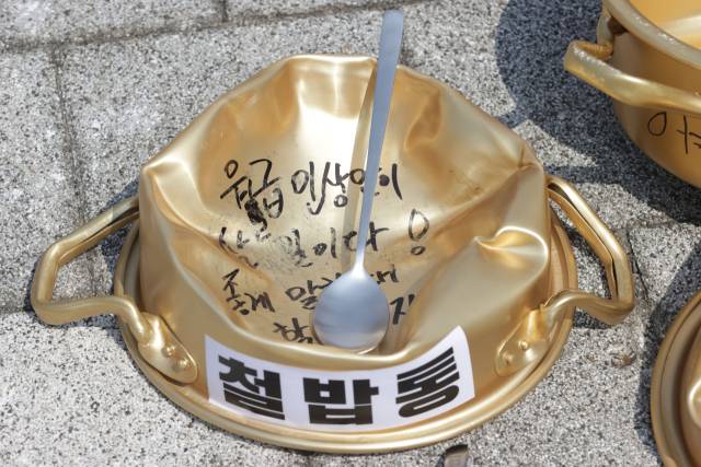 2024년 8월 6일 '청년 공무원 100인 기자회견'에서 참석자들이 문구를 적은 철밥통을 밟는 퍼포먼스를 하고 있다. 연합뉴스