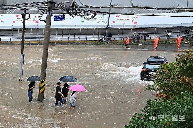 호우경보가 발효된 17일 광주 북구 중흥동 북구청4거리에서 전남대 방향으로 향하는 일반도로와 주택가에 물이 사람 종아리 높이까지 범람해 차량은 움직이지 못하고 시민들은 침수된 도로를 건너고 있다. 양광삼기자 ygs02@mdilbo.com