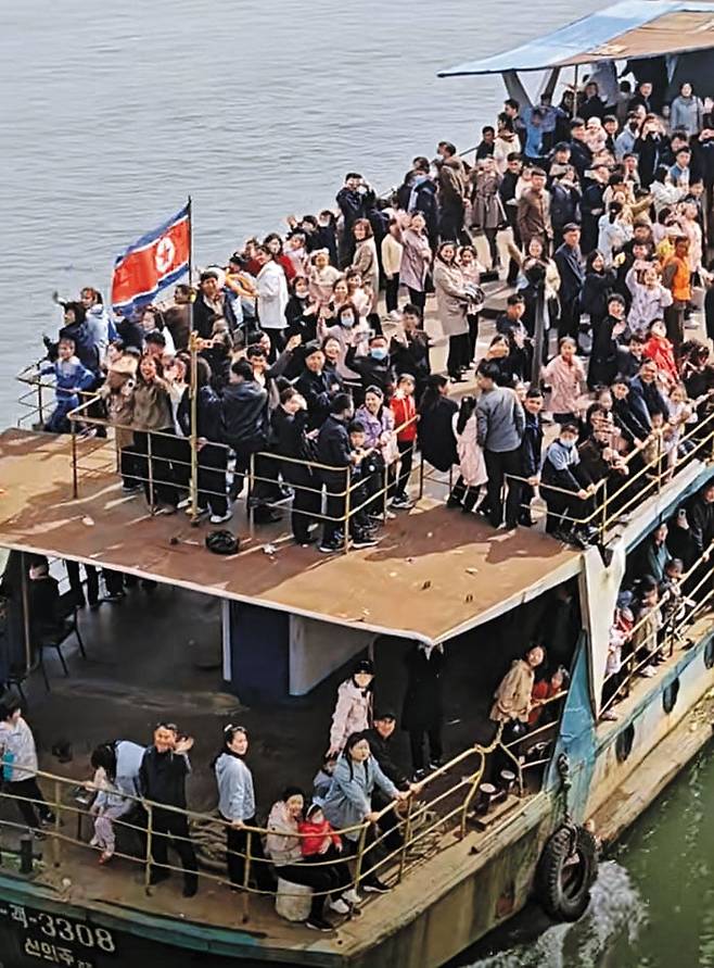 유람선 타고 中단둥 둘러보는 北주민들 - 지난 4월 북한 신의주를 출발해 중국 단둥 지역을 오가는 유람선에 탑승한 북한 주민들이 단둥 방면을 향해 손을 흔들어 보이고 있다. 코로나 팬데믹 이후 소원해졌던 북·중 관계가 최근 양국 간 관광이 재개되는 등 다시 회복될 조짐을 보이고 있다. /더우인