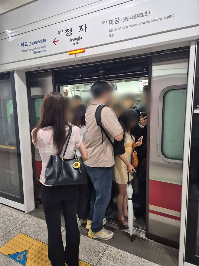 17일 오전 정자역에서 비에 젖은 우산을 손에 든 채 몸을 잔뜩 웅크리고 간신히 열차에 올라타는 시민들. 사진=김예지 기자