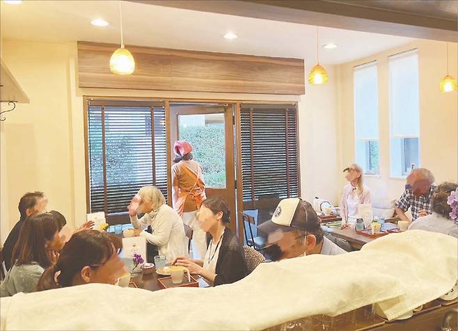 오렌지 데이 센가와는 한 달에 한번 ‘우크라이마 식당’에서 진행된다. 보통 치매 환자 2명과 오렌지 데이 센가와 운영위원회 봉사자가 함께 근무한다. 사진 위에는 뒤편이 한나 아키코 오렌지 데이 센가와 운영위 대표. 오렌지 데이 센가와는 누구나 와서 음료나 디저트를 먹을 수 있다. 다만 따뜻한 음료는 미지근하게 제공되고 주문 실수가 발생하기도 한다. 하지만 그 누구도 불만 섞인 목소리를 내지 않는다. 오히려 주문 실수에 웃음꽃이 번진다. (오렌지 데이 센가와 제공)