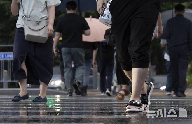 [서울=뉴시스] 김근수 기자 = 서울지역에 강한 비가 내리는 가운데 17일 서울 종로구 세종대로에서 한 시민이 슬리퍼를 신고 출근길에 나서고 있다. 2025.07.17. ks@newsis.com