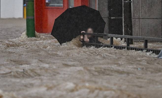 광주 지역에 폭우가 쏟아진 지난 17일 오후 침수된 광주 북구청 앞 도로에서 한 시민이 난간을 붙잡고 물살을 버티고 있다 (사진=뉴시스)
