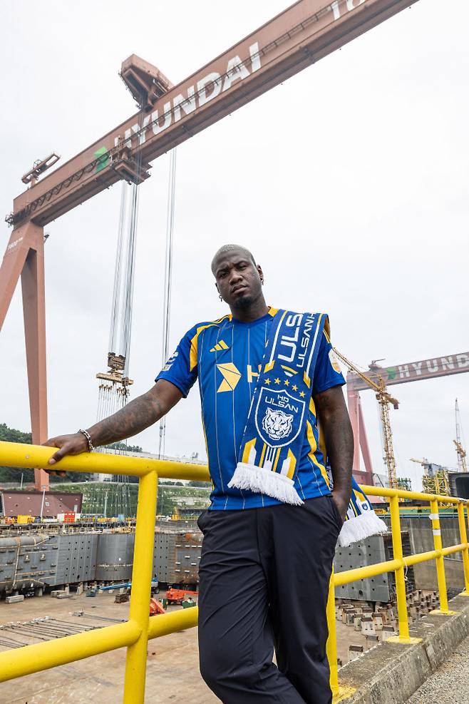 울산 HD 유니폼을 입은 말컹이 HD현대중공업 해양 야드 H-도크 ‘골리앗 크레인’ 앞에서 입단 촬영을 하고 있다. 사진=울산 HD